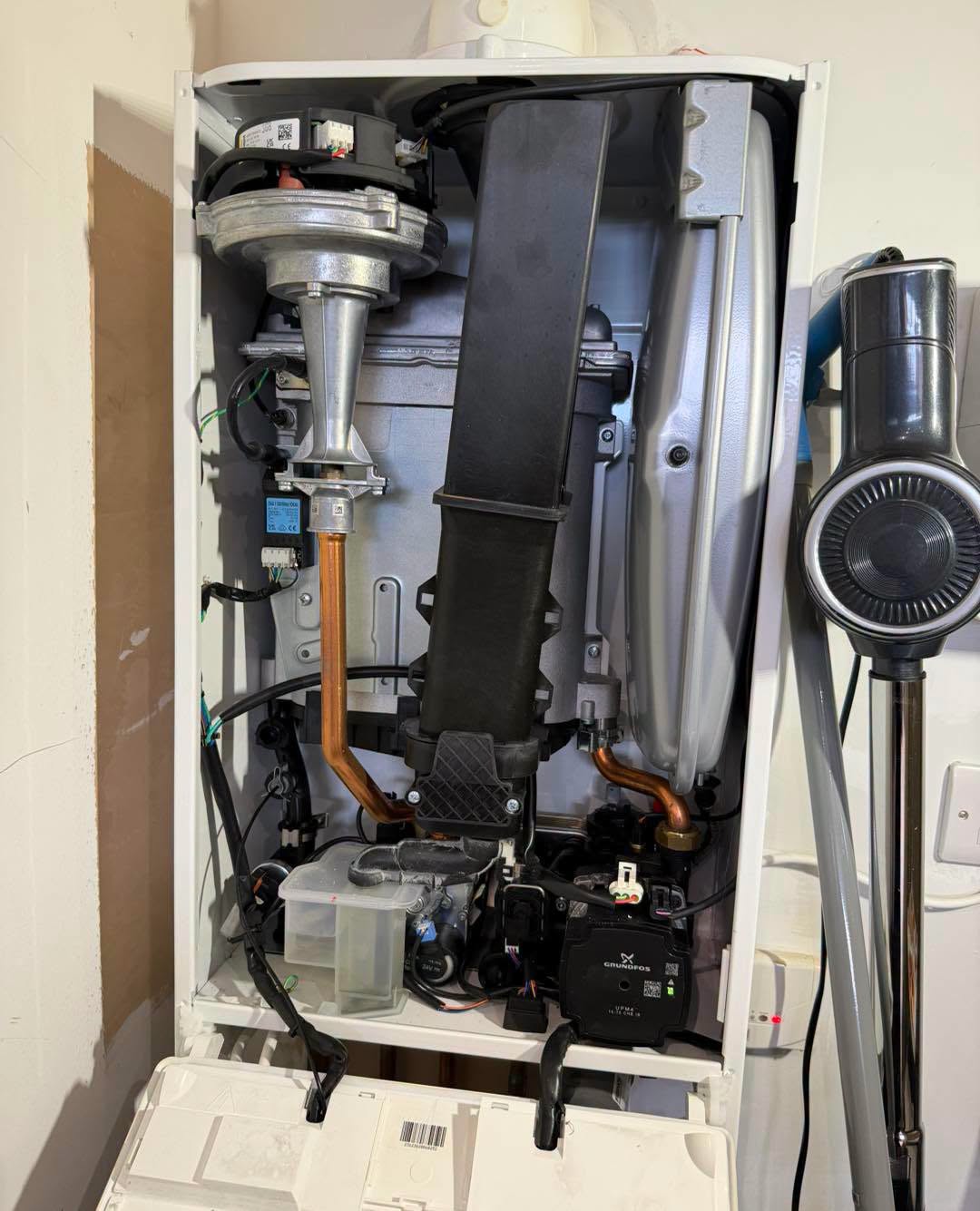 A boiler opened to show the fan, pump and internal pipework