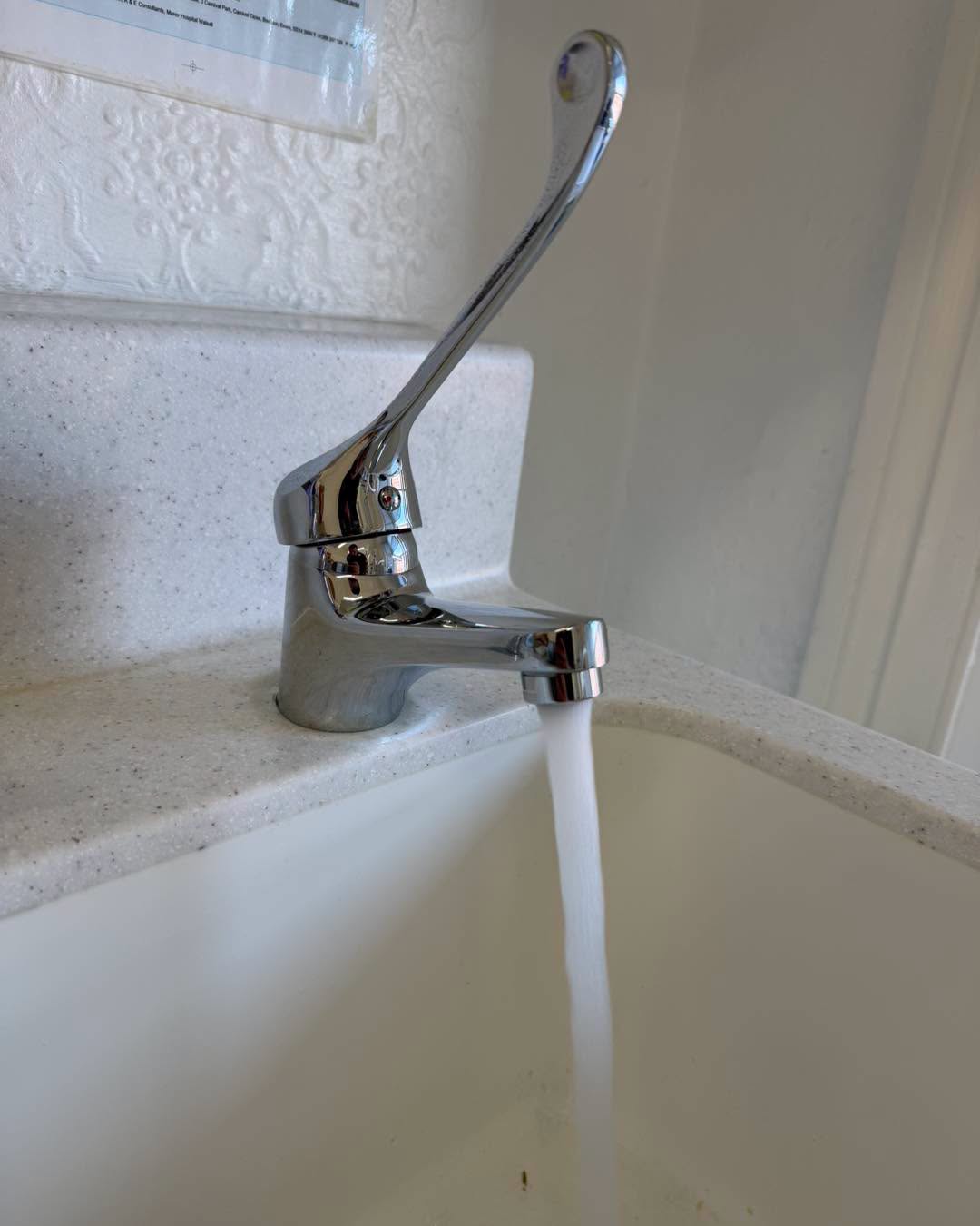 Lever tap into a white basin.