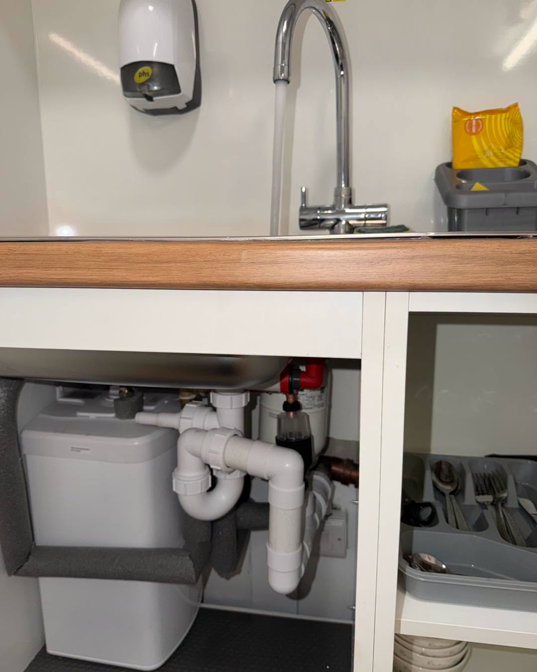 Waste, trap and softener under a commercial sink.